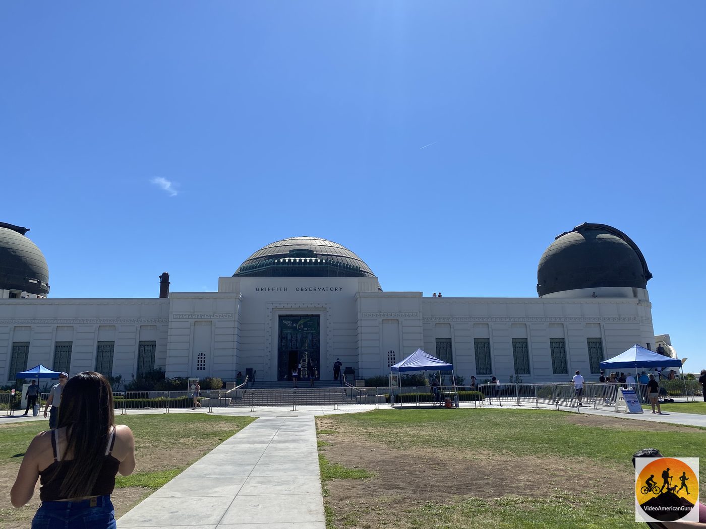 Griffith Observatory's white domes above the front lawn on a clear blue day